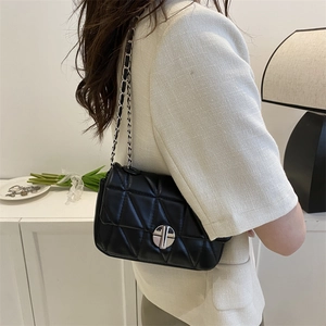 Minimalist black quilted crossbody bag with silver chain strap shown on model shoulder