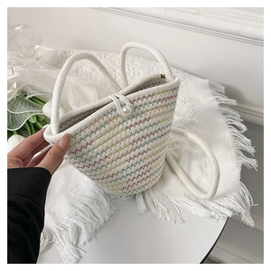 Dettaglio della borsa a secchiello intrecciata con motivi colorati e chiusura con perla