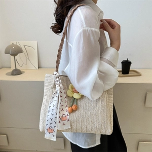Minimalist beige woven straw tote bag with floral pendant and scarf in a lifestyle setting