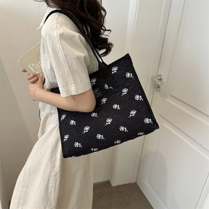 Large black tote bag featuring white rose jacquard pattern and fashion label for women