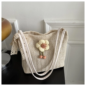Détail d'un sac cabas en paille fait main avec breloque fleurie 3D et ruban en dentelle