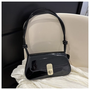 Detail of black patent leather shoulder bag with gold metal twist lock and knot strap