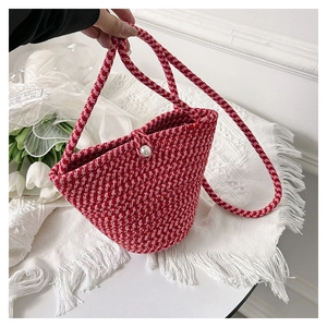 Dettaglio della borsa a secchiello intrecciata rossa e rosa con chiusura a perla