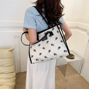 Fashionable white tote bag with black rose patterns and shoulder straps for daily commute