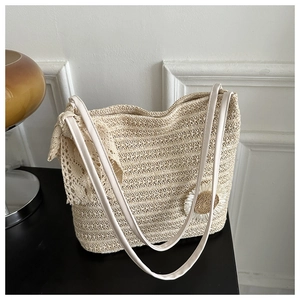 Détail d'un sac cabas tissé beige avec nœud en dentelle et ornement floral de marguerite