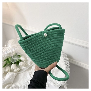 Dettaglio della borsa a secchiello verde intrecciata con chiusura a perla grande