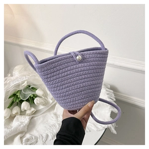 Dettaglio della borsa a secchiello viola intrecciata con chiusura a perla bianca