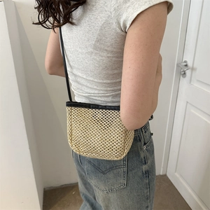 Minimalist handmade straw bucket bag with black leather trim and shoulder strap