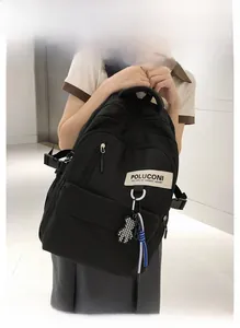 Détail d'un sac à dos en nylon noir avec pendentif ours à damier et étiquette de marque