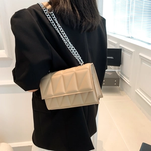 Beige geometric quilted crossbody bag with silver chain strap shown on model shoulder