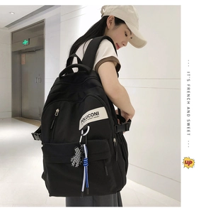 Vue latérale du sac à dos en nylon noir avec pendentif à damier et patch de marque
