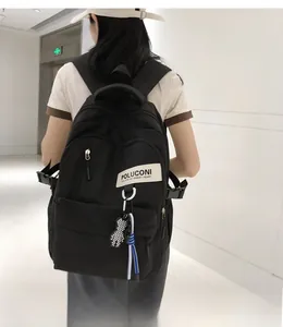 Détail du sac à dos en nylon noir avec étiquette POLUCONI et breloque ours à damier