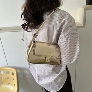 Chic champagne gold underarm bag in glossy metallic finish with elegant knot shoulder strap