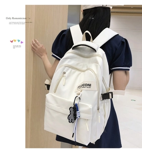 Détail d'un sac à dos en nylon blanc style collège avec logo POLUCONI et pendentif