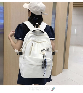 Vue détaillée du sac à dos blanc en nylon avec poche zippée et charm d'ours à carreaux