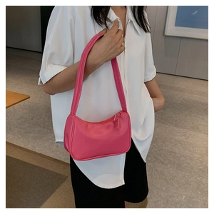 Model wearing a rose pink faux leather shoulder bag with zipper and matte finish
