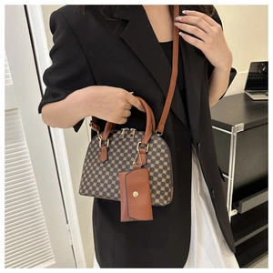 Detail of vintage patterned shell bag with brown double handles and golden hardware accents