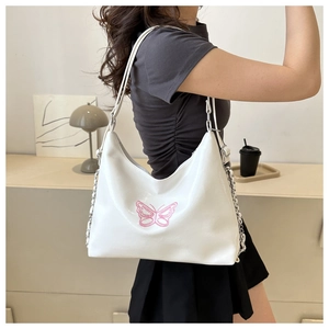 Nahaufnahme der weißen Lederschultertasche mit rosa Schmetterlingsstickerei und Metallkette
