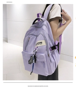 Détail du sac à dos en nylon violet avec boucle latérale et breloque cœur à damier