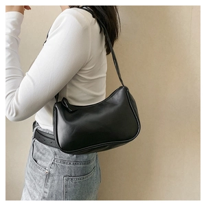 Minimalist black hobo shoulder bag shown in profile with smooth faux leather texture