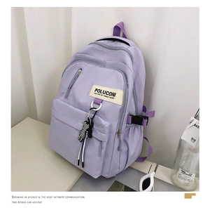 Détail d'un sac à dos en nylon violet clair avec étiquette de marque et breloque