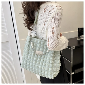 Detail of light green quilted tote bag with pearl chain and leather shoulder strap