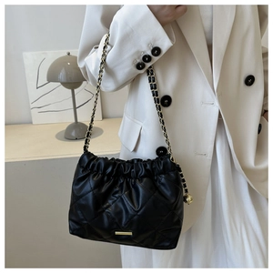Detail showing black quilted leather crossbody bag with elegant chain strap on shoulder