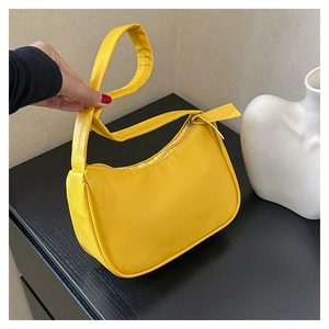 Close-up of vibrant yellow crescent-shaped underarm bag in smooth vegan leather