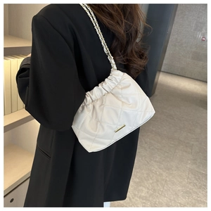 Detail of off-white quilted shoulder bag with chain strap and gold hardware on black blazer
