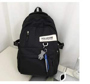 Détail du sac à dos en nylon noir avec étiquette blanche et breloque ours à damier chic