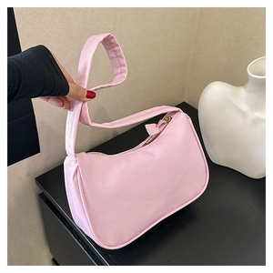 Detail view of pink minimalist synthetic leather hobo bag with zip closure held by hand