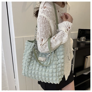 Detail of light green tote bag featuring bubble texture and elegant pearl strap