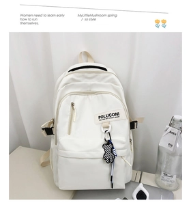 Détail du sac à dos en nylon beige avec breloque ours à carreaux et fermetures éclair contrastées