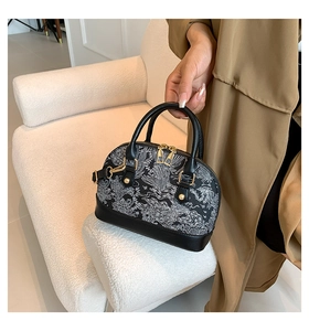 Détail d'un mini sac coquille noir et blanc à motif floral avec finitions dorées