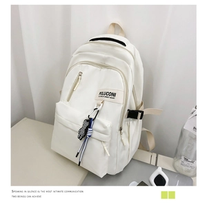 Gros plan d'un sac à dos blanc minimaliste avec fermeture éclair et breloque damier