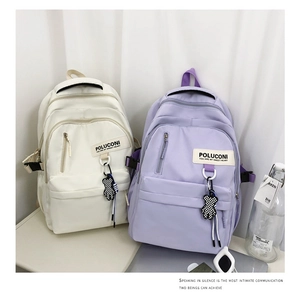 Vue détaillée des sacs à dos en nylon crème et violet avec pendentifs d'ours à carreaux
