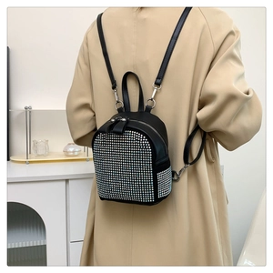 Mini black leather backpack with silver rhinestones shown on model in khaki trench coat