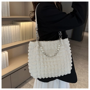 Detail of white bubble textured tote bag featuring pearl chain and leather straps