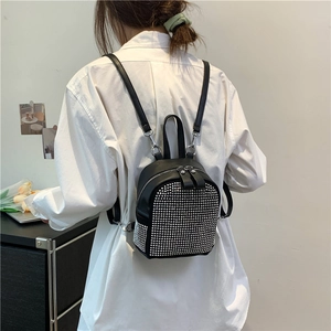 Chic black leather mini backpack with silver rivets shown on model in a modern room