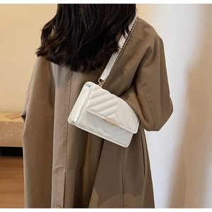 Detail of white chevron quilted crossbody bag with gold metallic buckle and chain strap