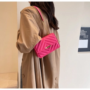 Close-up of rose red quilted crossbody bag with V-pattern stitching and gold metal buckle