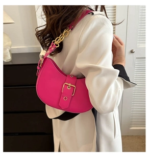 Détail du sac baguette rose rouge avec chaîne dorée porté comme un sac à l'épaule