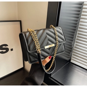 Detail of black chevron quilted faux leather bag with elegant gold chain strap