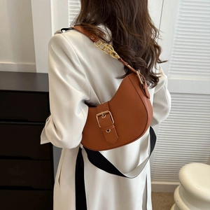 Sacoche marron en cuir avec boucle dorée et bandoulière chaîne portée par un mannequin