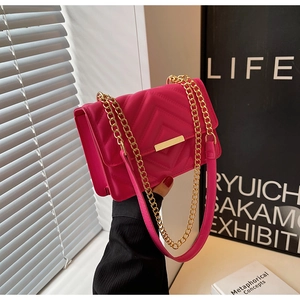 Detail of hot pink quilted crossbody bag with gold metal chain and bar closure