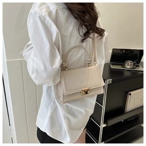 Detail of cream crocodile embossed small square handbag with knot handle and gold buckle