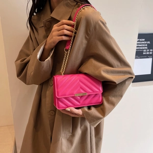 Stylish rose pink quilted crossbody bag with gold chain strap on beige trench coat