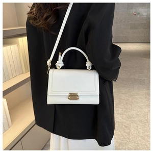 Detail of white crocodile pattern bag with knot handle and gold buckle on shoulder