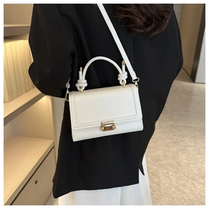 Detailed side view of white faux crocodile leather handbag with twisted handle and gold clasp