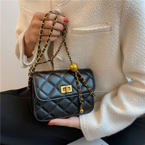 Detail of quilted leather texture and gold-tone ball chain adjuster on black bucket bag